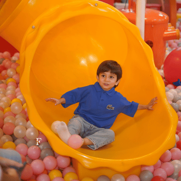 Child enjoying a colourful indoor slide into a ball pit at Wooray Delhi.