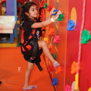Girl climbing an indoor rock climbing wall at Wooray Delhi play area.