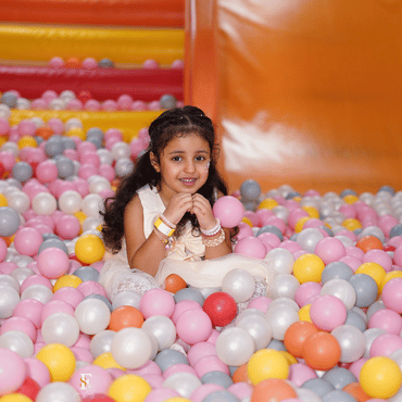 Girl enjoying colourful ball pit play at Wooray Delhi indoor play area.