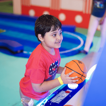 Child playing a basketball arcade game at Wooray Delhi indoor play area.