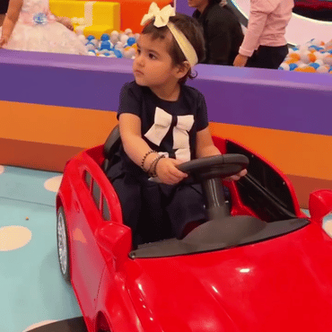 Girl enjoying a red kids' car ride at Wooray Dehradun indoor play area.