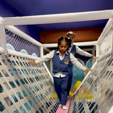 Children walking across a rope bridge in the indoor play area at Wooray Dehradun.