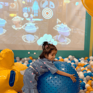 Child enjoying an interactive ball game in the indoor play area at Wooray Dehradun.