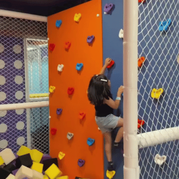 Child climbing an indoor rock climbing wall at Wooray Dehradun.