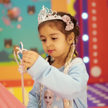 Child wearing a princess costume and holding a tiara at Wooray Dehradun.