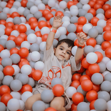 Child enjoying playful fun in a colourful ball pit at an indoor play area.