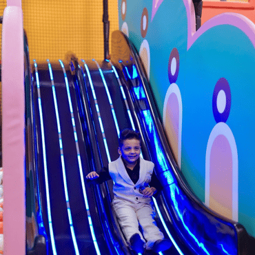 Child enjoying a colourful indoor slide at a kids play area.