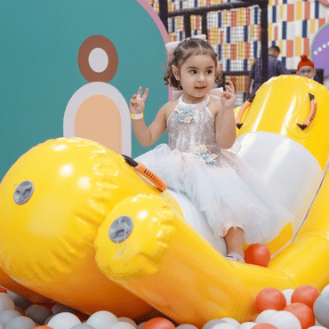 Girl enjoying a colourful inflatable ride in an indoor play area.